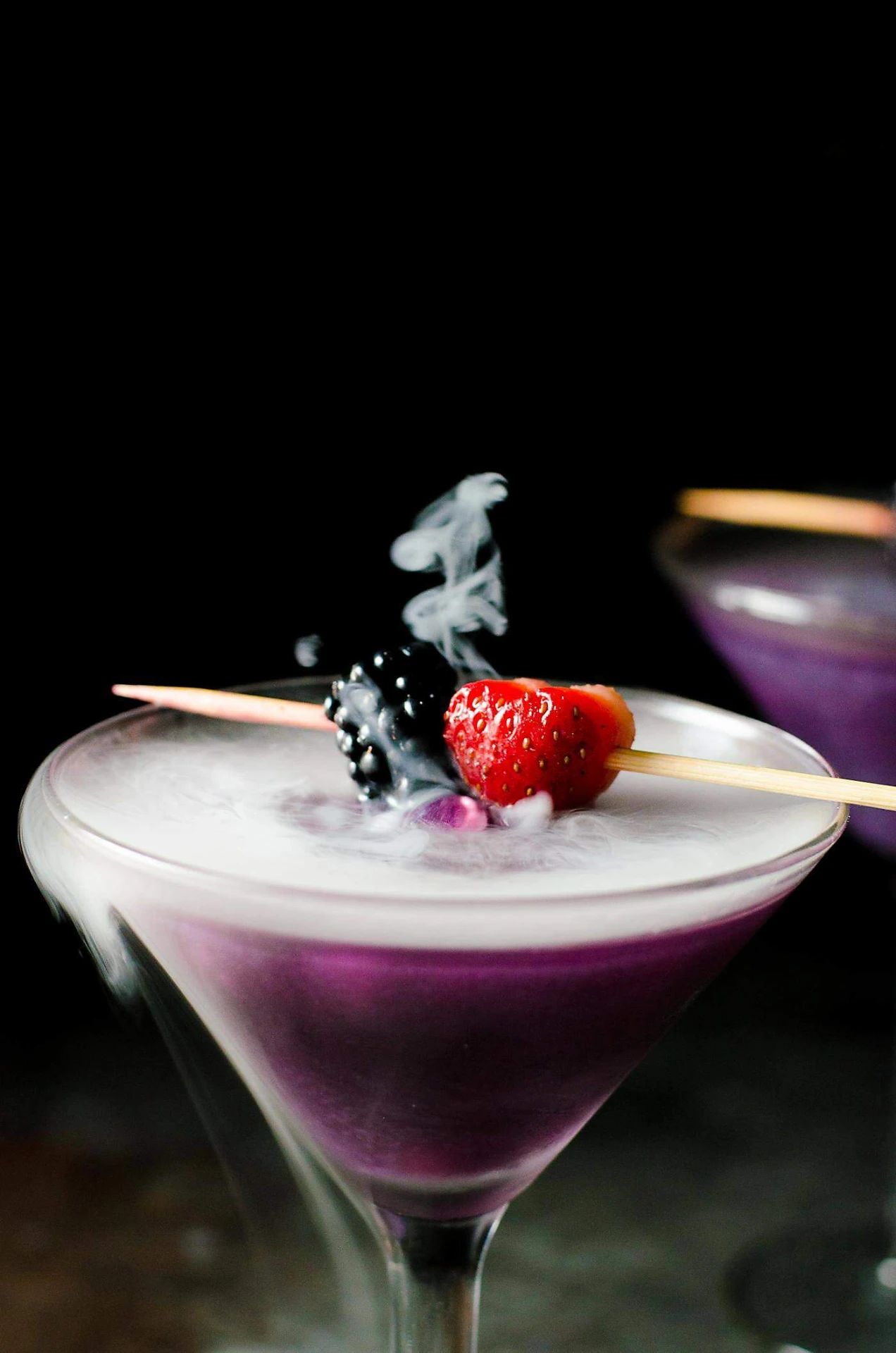 Violet martini with berry skewer and drifting smoke